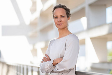 Entrepreneur in business casual standing with arms crossed at office building terrace