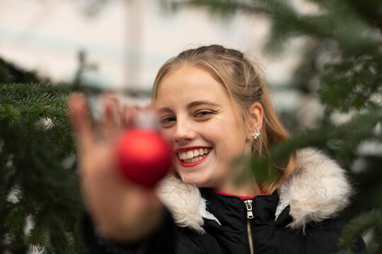 Happy young woman showing Christmas ornament during holidays