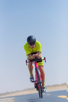 Determined male cyclist riding bicycle on road at desert, Dubai, United Arab Emirates