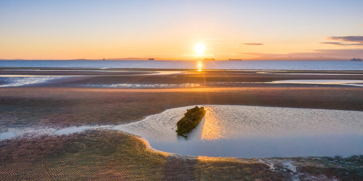 UK, Scotland, Wreck of X-Craft submarine lying on shore of Aberlady Bay at sunset