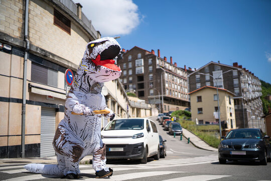 Large toy dinosaur with bread walking on zebra crossing in city