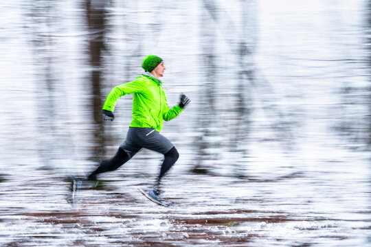 Young sportsman running in speed at forest during cold temperature