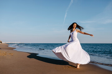 Ballerina in white dress dancing at the sea