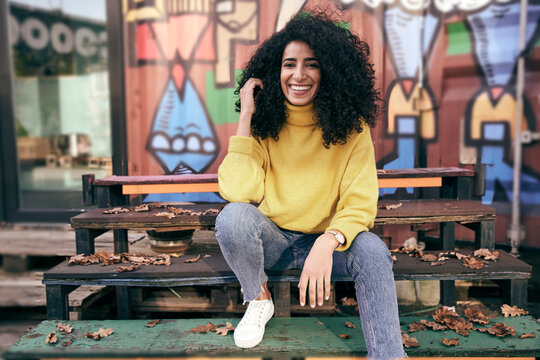 Beautiful woman with curly hair sitting on steps in city during autumn