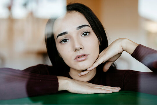 Portrait of young woman behind windowpane