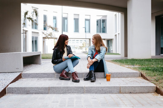 Young female university students sitting on steps at campus