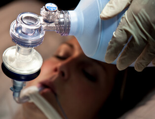 Hand of doctor holding oxygen ambu bag to patient in ICU