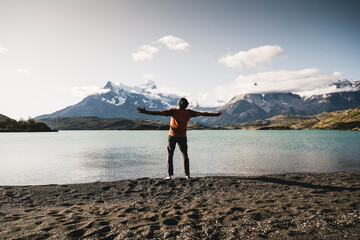 Man with arms outstretched standing at Lake Pehoe in Torres Del Paine National Park Patagonia, South America