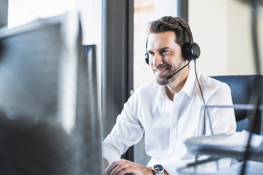Businessman wearing headphones using computer while sitting at office