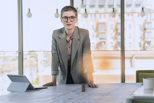 Portrait of confident businesswoman leaning on desk in office