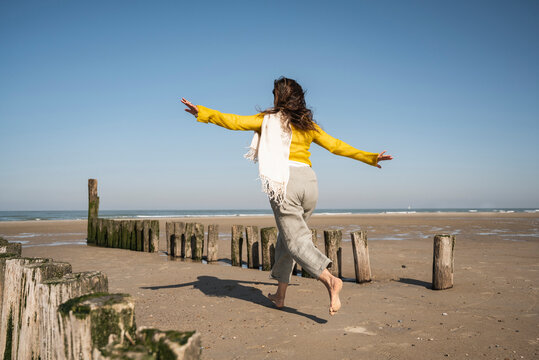 Carefree woman running at beach against clear sky