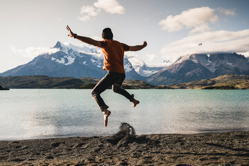 Man with arms outstretched jumping at Lake Pehoe in Torres Del Paine National Park Patagonia, South America