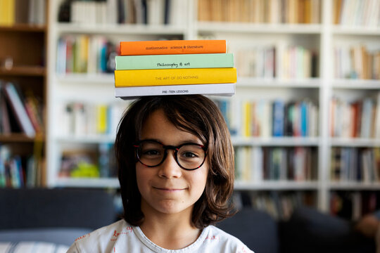 Portrait of smiling boy balancing stack of books on his head