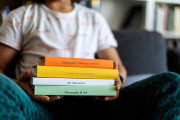 Crop view of boy holding stack of four books