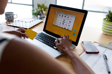 Businesswoman sitting in office using laptop to make an online payment with credit card