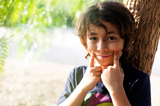Portrait of boy pulling corner of mouth with his fingers