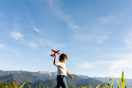 Boy holding airplane toy while walking against clear sky