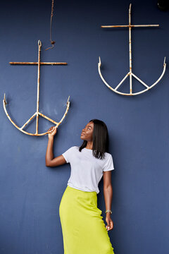 Young woman in front of blue background looking at anchor hanging at wall