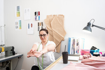 Seamstress stretching her hands in tailor shop