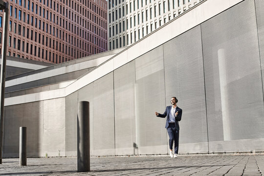 Businessman with headphones dancing against wall