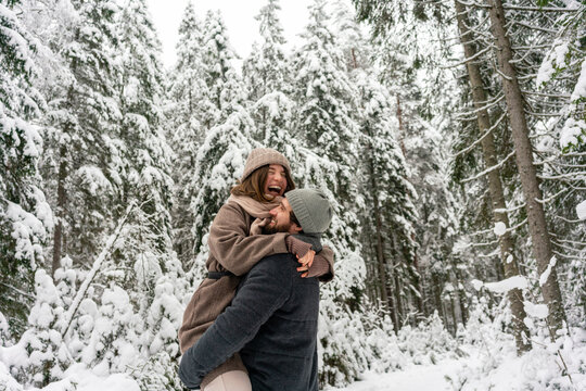 Young man carrying woman in arms while standing in forest