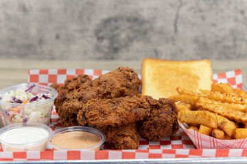 Spicy hot chicken wings piled with french fries, cole slaw, toast, and two dipping sauces