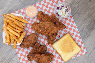 Overhead view of full table feast full of crispy and spicy chicken wings and strips served with french fries, cole, slaw, ranch, and secret dipping sauce