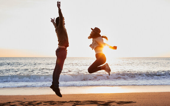 Carefree boyfriend and girlfriend enjoying while jumping against sea