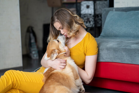 Woman cuddling with her dog in living room at home