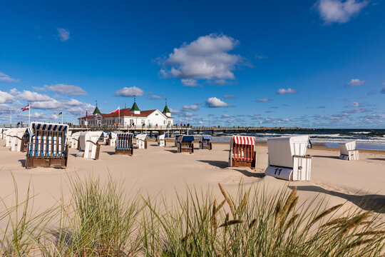 Germany, Mecklenburg-Western Pomerania, Heringsdorf, Hooded beach chairs on empty beach with Ahlbeck Pier in background