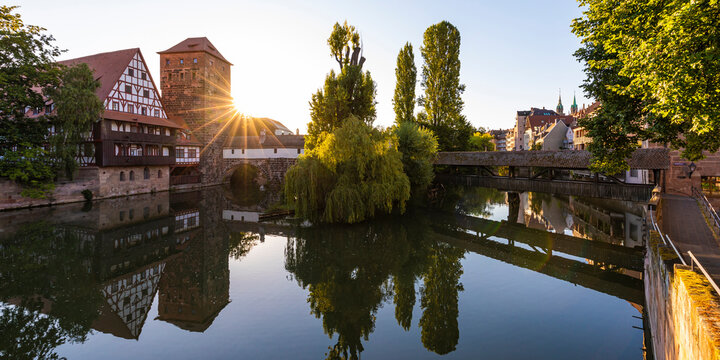 Germany, Bavaria, Nuremberg, Henkersteg, Weinstadel and Wasserturm reflecting in river Pegnitz at sunset