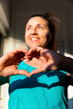 Laughing woman making heart shape with her fingers in front of chest
