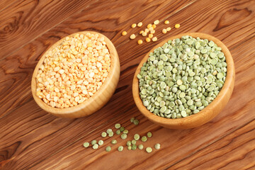 Dry chopped yellow and green peas in bamboo bowls on a wooden table. Closeup