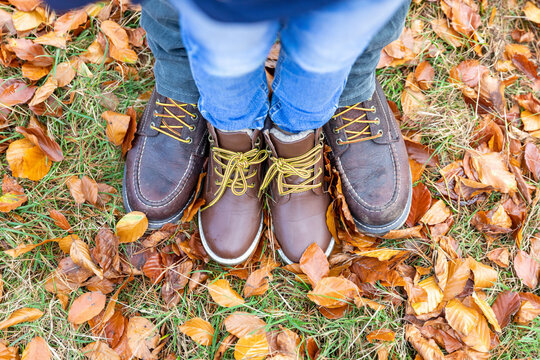 Father and son wearing leather shoe standing together on fallen leaf