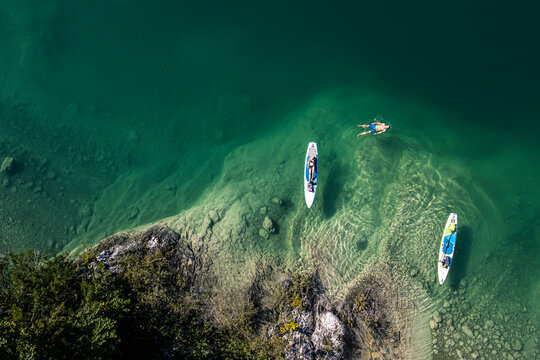 Germany, Bavaria, Aerial view of two paddleboarders relaxing on green shore of Lake Walchen