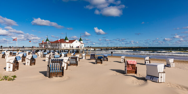 Germany, Mecklenburg-Western Pomerania, Heringsdorf, Hooded beach chairs on empty beach with Ahlbeck Pier in background