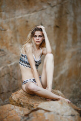 Obraz premium Young girl in bikini on the ocean shore. Stone background. Portrait of a Caucasian girl with European facial features.