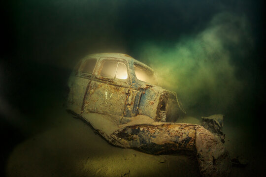 Underwater view of rusty car wreck deteriorating at bottom of Lake Atter