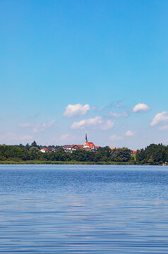 Germany, Bavaria, Leobendorf, Sky over blue water of Abtsdorfer See in summer with village in background