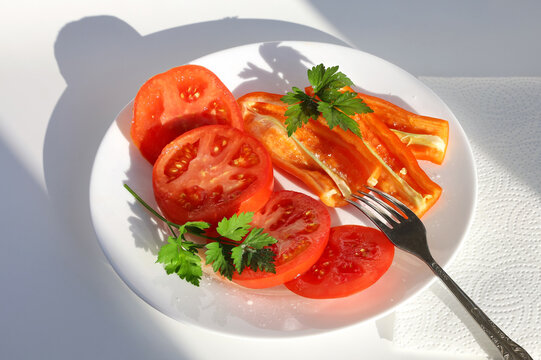 Pieces of tomato, sliced bell pepper and parsley on white plate with fork