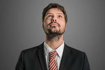 thinking businessman in front of a grey wall