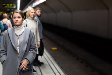 Obraz na płótnie Canvas Attractive brunette waiting for train on platform of underground station ..