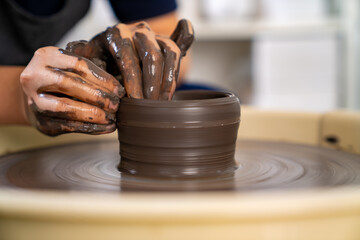  Asian woman sculptor artist hands sculpture clay on pottery wheel at ceramic studio. Female craftsman molding raw clay create pottery shapes at workshop. Small business handicraft product concept.