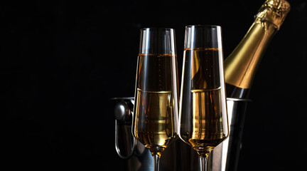Two champagne glasses and and bottle in bucket on black background. Happy New Year or Merry Christmas composition