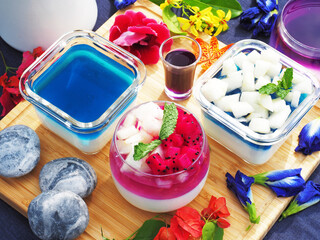 Butterfly pea flower milk jelly topped with fruit and mint in glass jars 