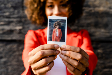 Woman's hands holding instant photo of herself, close-up