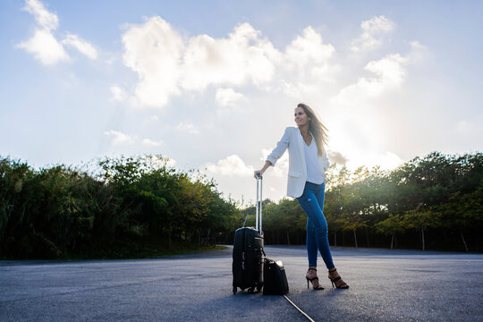Businesswoman with baggage standing on a remote road