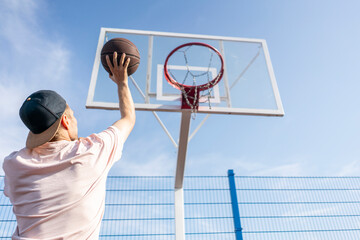 young huy score a basketnall in the hoop outdoors on the sport court