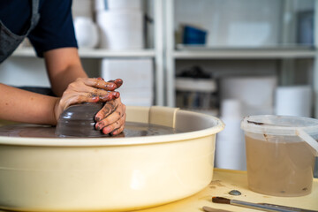  Asian woman sculptor artist hands sculpture clay on pottery wheel at ceramic studio. Female craftsman molding raw clay create pottery shapes at workshop. Small business handicraft product concept.