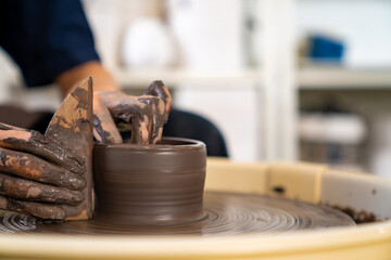  Asian woman sculptor artist hands sculpture clay on pottery wheel at ceramic studio. Female craftsman molding raw clay create pottery shapes at workshop. Small business handicraft product concept.
